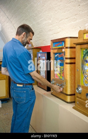 L'uomo gioca un penny slot machine nelle memorie meccanica Museo di divertimenti, Kings Road archi, Brighton Foto Stock