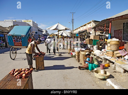 Rue du Marche scena con bancarelle del mercato, per la vendita di carni fresche, cestelli etc e un pousse-pousse rickshaw, Tulear / Toliara, Atsimo Andrefana, Madagascar Foto Stock