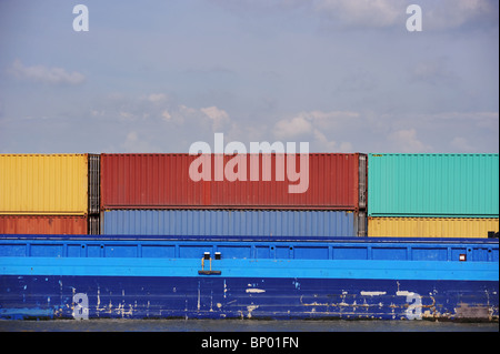 Un carico colorato contenitori impilati sul ponte di una nave Foto Stock