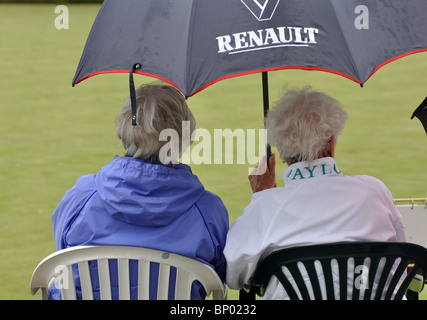 Le donne con ombrello signore guardare partite di bocce Foto Stock