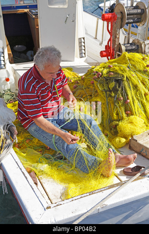 Un pescatore riassettando le reti al porto del villaggio principale di Antiparos Isola, Cicladi, ISOLE DELL' EGEO, Grecia Foto Stock