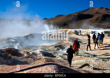 I turisti in mezzo alle piscine di fango bollente al Sol de Manana Geyser Basin in Bolivia. Foto Stock