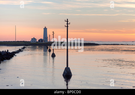 Tramonto al mare Grotta, Islanda. Il faro con il ghiacciaio Snaefellsjokull in distanza Foto Stock