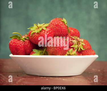 Bacche mature di una fragola in una piastra di porcellana su un tavolo Foto Stock