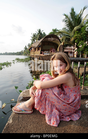 India Kerala. Giovane ragazza su una vacanza in famiglia in Kerala Backwaters, houseboat in background. (MR) Foto Stock