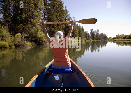 Una donna paddling una canoa sul fiume Deschutes, Oregon Foto Stock