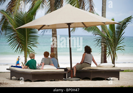 Kenya, Costa, la spiaggia di Diani. Una famiglia si affacciano sulla spiaggia di Diani da sedie a sdraio a Almanara Beach Resort. (MR) Foto Stock
