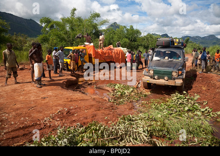 Mozambico, nei pressi di Nampula. Un 4x4 aziona attorno a un carrello bloccato nel fango. Foto Stock