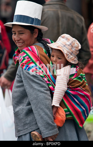 Il Perù, una donna peruviana con il suo bambino sulla schiena negozi al mercato Santuranticuy, tenutasi in Cusco alla vigilia di Natale ogni anno. Foto Stock