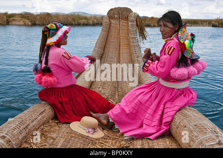 Il Perù, due ragazze da Uros fila un reed barca a uno degli unici isole galleggianti del lago Titicaca. Foto Stock