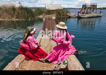 Il Perù, due ragazza di Uros fila un reed barca a uno degli unici isole galleggianti del lago Titicaca. Foto Stock