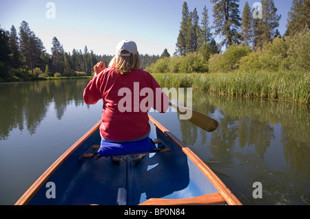 Una donna paddling una canoa sul fiume Deschutes, Oregon Foto Stock