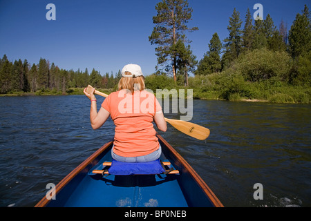 Una donna paddling una canoa sul fiume Deschutes, Oregon Foto Stock