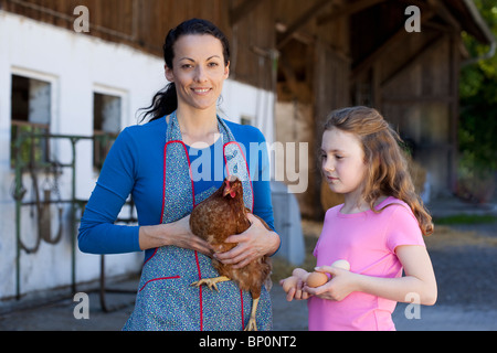 Farmwoman con hen, figlia con uova Foto Stock