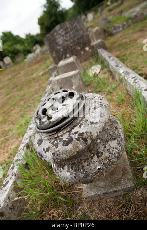 Vecchio weathered Stone flower pot su un unkempt grave in un villaggio inglese sagrato Foto Stock