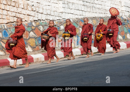 Il debuttante monaci camminare da un muro sul loro quotidiano Alms Foto Stock