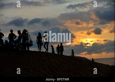 Persone che salgono sulle colline di sabbia, stagliano RISING SUN. Dune di sabbia rossa, Mui Ne, Vietnam Foto Stock