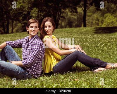 Licenza disponibile all'indirizzo MaximImages.com - giovane felice coppia sorridente ai primi trent'anni seduto sull'erba in un parco Foto Stock