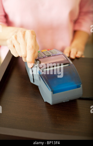 Primo piano di una donna ha avuto scorrendo una carta di debito attraverso uno scanner. Profondità di campo. Foto Stock