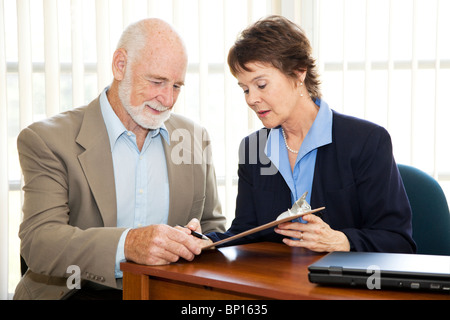 Senior uomo firma un contratto nel suo ufficio del procuratore. Foto Stock