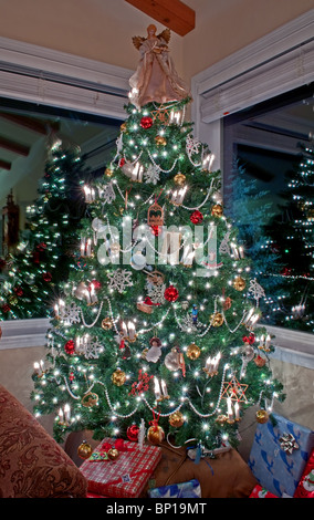 Colpo verticale di una piscina illuminata e albero di Natale decorato con due finestre che riflettono le luci e decorazioni, presenta. Foto Stock