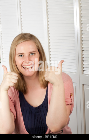 Giovani femmine gesticolando pollice in alto Foto Stock