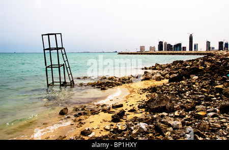 Guardando attraverso una spiaggia naturale con bagnino in disuso la torre verso terra recuperata a Doha in Qatar Foto Stock