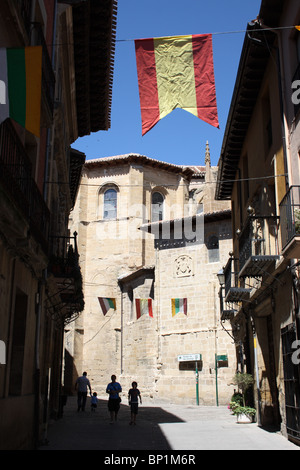 Visualizza in basso della strada di città vecchia cattedrale, Santo Domingo de la Caldaza, con bandiera spagnola tra tetti, La Rioja, Spagna Foto Stock