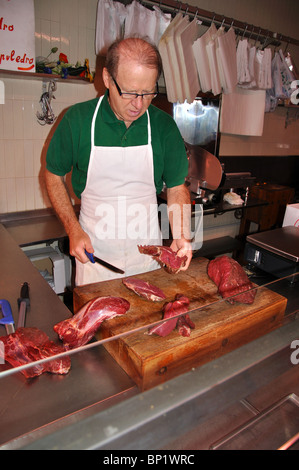 Butcher il taglio di carne in una macelleria a Venezia Italia Foto Stock