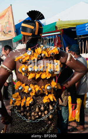Devoto indù con piccole lotas di acqua sospesa dal suo retro con ganci durante il Festival di Thaipusam a Grotte Batu Foto Stock