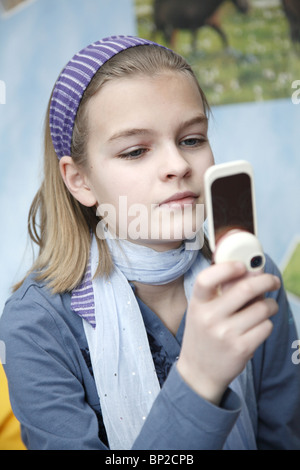 Un undici-anno-vecchia ragazza che gioca con il suo telefono cellulare, Amburgo, Germania Foto Stock