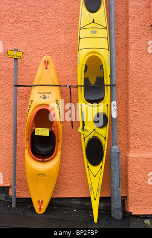 I kayak e canoe stare in piedi contro un muro shop a Oban, Scozia. Foto Stock