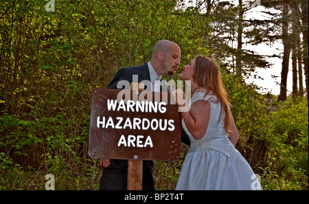 Avviso di matrimonio con un pericoloso segno di avvertimento con la sposa e lo sposo circa al bacio oltre il segno. Divertente Concetto di immagine. Foto Stock