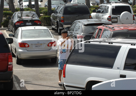 Un giovane ragazzo asiatico aiuta a guidare i suoi genitori all'indietro in una posizione di parcheggio. Foto Stock