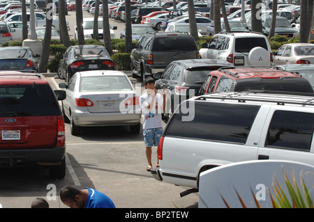 Un giovane ragazzo asiatico aiuta a guidare i suoi genitori all'indietro in una posizione di parcheggio. Foto Stock