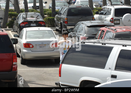 Un giovane ragazzo asiatico aiuta a guidare i suoi genitori all'indietro in una posizione di parcheggio. Foto Stock