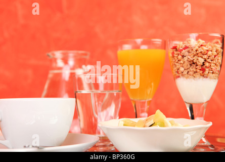 Una sana colazione costituita da una insalata di frutta, bicchiere di succo di frutta, caffè, cereali, yogurt e un bicchiere di acqua Foto Stock