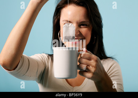 Una giovane donna tiene un sacchetto da tè su una tazza di acqua calda. Foto:Jeff Gilbert Foto Stock