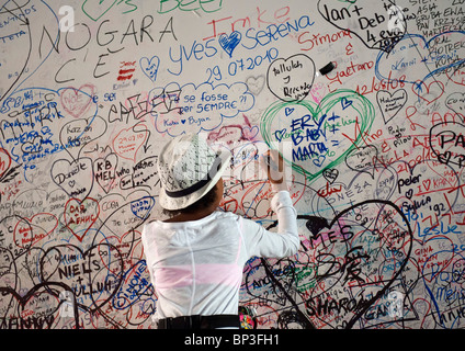 Una giovane ragazza scrive un messaggio sulla parete dell'amore, Verona, Italia Foto Stock