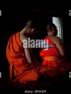 Un monaco Junior legge da un libro di pagatore durante un pomeriggio sessione di preghiera, Wat Pho e Wat Phra Chetuphon, Bangkok, Thailandia Foto Stock