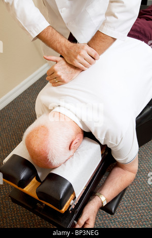 Primo piano di chiropratici mani di regolazione di un uomo anziano della spina dorsale. Foto Stock