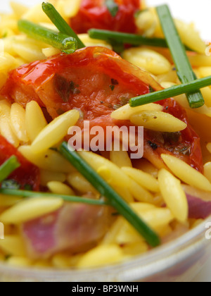 Orzo Riso pasta a forma di sole asciugato insalata di pomodoro nel recipiente di vetro su uno sfondo bianco Foto Stock