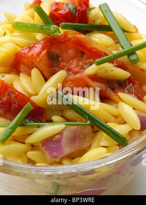 Orzo Riso pasta a forma di sole asciugato insalata di pomodoro nel recipiente di vetro su uno sfondo bianco Foto Stock