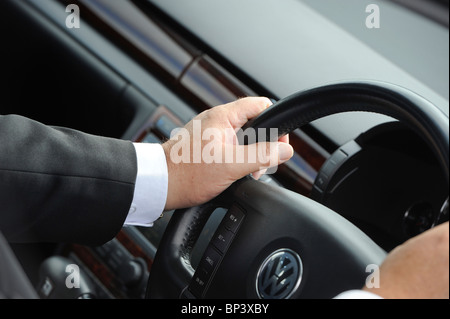 Un imprenditore al volante di una vettura Volkswagen. Foto Stock