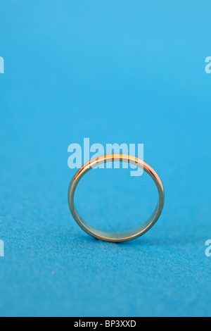 Close up di oro wedding band o anello su sfondo blu Foto Stock