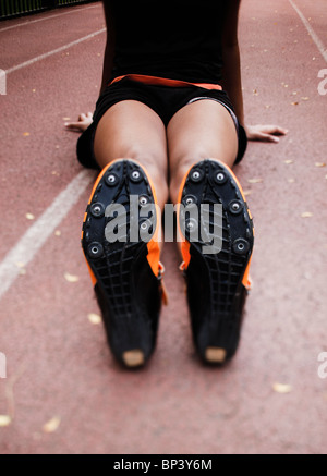 African American sprinter girl stretching gambe su di una traccia Foto Stock