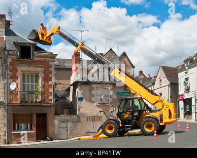 Antenna televisione essendo dotato di camino dall uomo in piedi (nessuna attrezzatura di sicurezza) in JCB movimentatore telescopico benna - Francia. Foto Stock