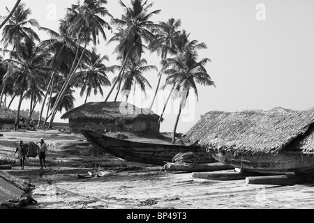 I pescatori portano le loro attrezzature home barche del passato e cottage vicino al villaggio di Varkala Kerala, India. Bianco e nero look rétro Foto Stock