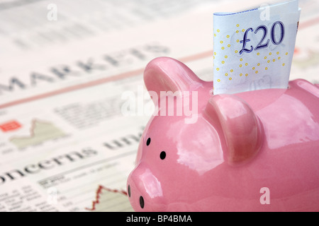 Rosa salvadanaio con 20 pound nota seduto su una copia del Financial Times money markets sezione nel Regno Unito Foto Stock