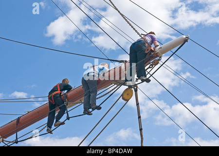 I membri di un equipaggio di un quadrato truccate veliero lavorando sul cortile centrale (Spar) di uno dei montanti. Foto Stock